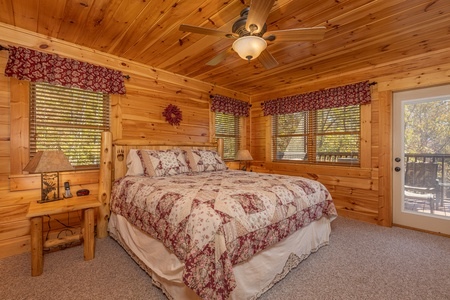 Bedroom with a log bed, two night stands, lamps, and deck access at Sensational Views, a 3 bedroom cabin rental located in Gatlinburg