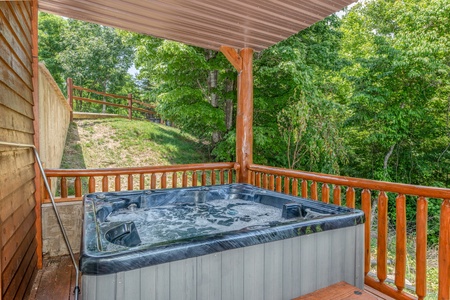 Hot tub on a covered deck with the yard behind it at God's Country, a 4 bedroom cabin rental located in Pigeon Forge