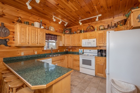 Breakfast bar and kitchen with white appliances at Hickernut Lodge, a 5-bedroom cabin rental located in Pigeon Forge