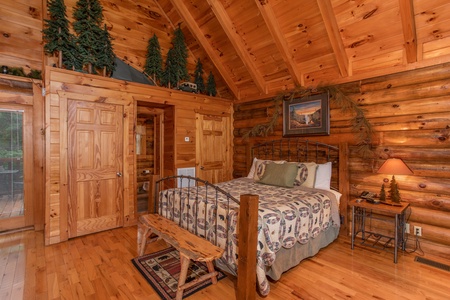 bedroom with queen bed and wooden bench at alpine sunset thrill a 1 bedroom cabin rental located in pigeon forge