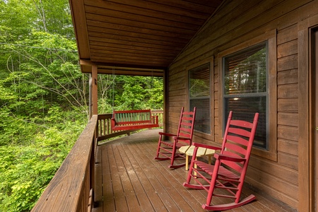 Swing and rocking chairs on a covered deck at Hawk's Heart Lodge, a 3 bedroom cabin rental located in Pigeon Forge