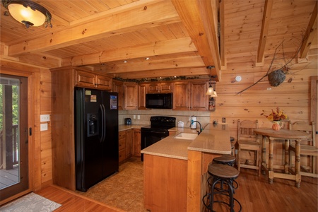 Kitchen with black appliances, counter top seating, and a high top dining table at Cedar Creeks, a 2-bedroom cabin rental located near Douglas Lake