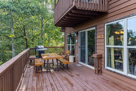 Dining table and gas grill on a deck at Bearing Views, a 3 bedroom cabin rental located in Pigeon Forge