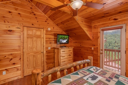 Bedroom with TV, dresser, en suite, and deck access at Four Seasons Lodge, a 3-bedroom cabin rental located in Pigeon Forge