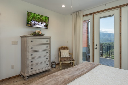 Dresser, TV, chair, and deck access at Mountain Celebration, a 4 bedroom cabin rental located in Gatlinburg