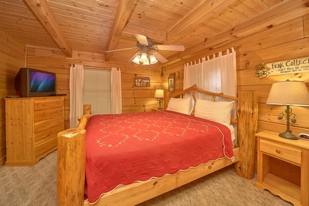 King sized log bed with dresser and television at A Place to Remember, a 2 bedroom cabin rental located in Gatlinburg