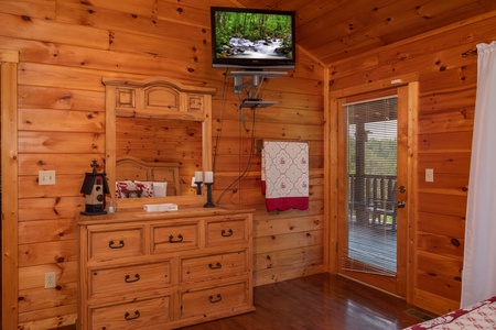 Bedroom with a dresser and mirror, a wall-mounted television, and deck access at Cabin Fever, a 4-bedroom cabin rental located in Pigeon Forge