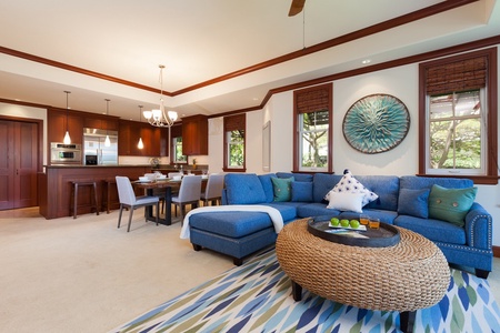 - Open concept living area with plush blue sectional and woven coffee table   - Flows seamlessly into dining area and gourmet kitchen with rich wood cabinetry   - Bright, inviting design perfect for gatherings or quiet relaxation