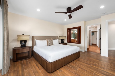 Unwind in your spacious bedroom featuring rich wood finishes, plush bedding, and a gentle ceiling fan for perfect temperature control.