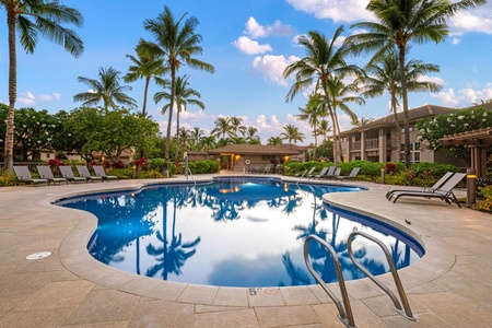 Sparkling pool with curved edges framed by palm trees and blue skies.
