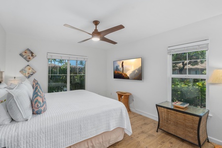 Comfy guest bedroom with dual garden windows and mounted TV.