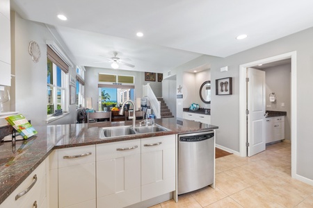 - Spacious kitchen island with dual sinks overlooks a cozy open living space - Stainless steel dishwasher and full view of living and dining areas enhance flow - Natural light fills the room through windows and glass patio doors