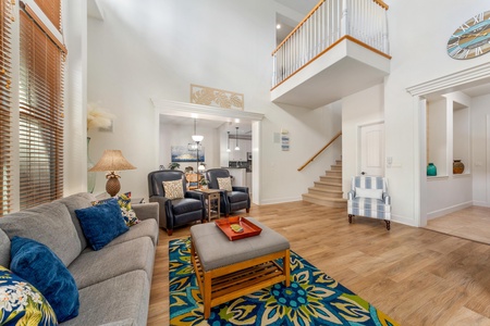 Sink into plush seating in your bright, open living space where coastal charm meets modern comfort beneath soaring ceilings.