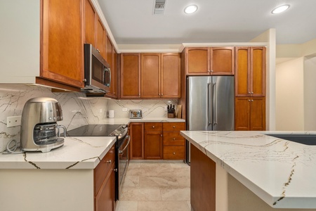 Your gourmet kitchen awaits with marble countertops, warm wood cabinets, and stainless steel appliances for memorable meal preparation.