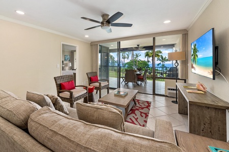 - Bright living space with neutral tones and red accents opens to a private lanai - Enjoy ocean views through sliding doors while relaxing in plush and wicker seating - Ceiling fan, tile floors, and natural textures create breezy indoor comfort