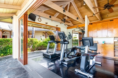 Your private fitness center blends seamlessly with the outdoors through wide-open doors, letting fresh island breezes energize your workout while you stay active on premium cardio equipment.