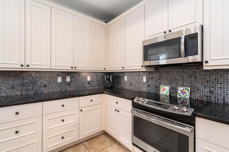 - Sleek stainless steel range and microwave anchor this chef ready space - Dark mosaic backsplash and white cabinetry create timeless contrast - Plenty of prep space and storage for extended stays or family meals