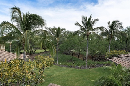 Lush tropical landscaping with swaying palms and manicured lawns creates a serene garden paradise surrounding the property.