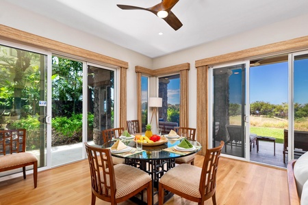 - Bright dining nook surrounded by windows framing greenery and open skies - Round glass table with cushioned wood chairs creates a welcoming spot for shared meals - Easy access to outdoor seating through sliding doors for indoor outdoor dining pleasure