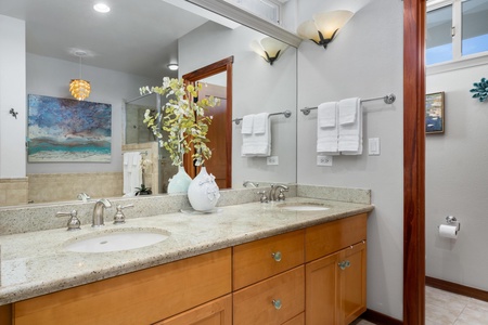 - Bathroom with dual sink vanity, granite countertop, and wood cabinetry - Large mirror and wall mounted lighting create a bright, spacious feel - Perfect for couples or families needing extra counter space