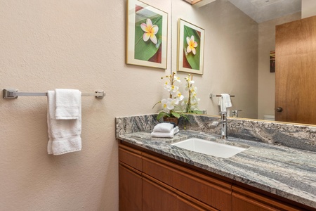Refresh in your beautifully appointed bathroom featuring elegant granite countertops, fresh towels, and tropical-inspired décor that brings island tranquility to your daily routine.