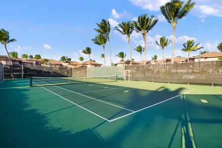 On-site tennis court framed by swaying palm trees and sunny skies—perfect for staying active during your tropical getaway.