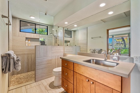 - Spa style bathroom with walk in shower natural tile and full vanity mirror - Sleek wood cabinetry paired with under sink lighting creates a polished look - Window brings in sunshine while maintaining privacy with frosted glass