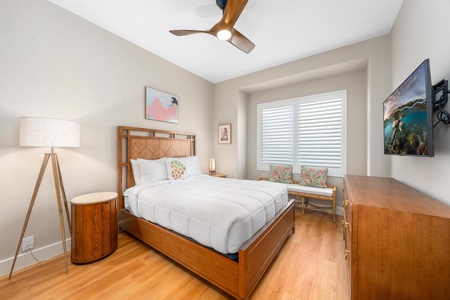 - Cozy guest bedroom with wood bed frame and matching side tables for a cohesive look - Large window with shutters brings in natural light while offering privacy - Decorative pillows and bench seating add comfort and style to the inviting space