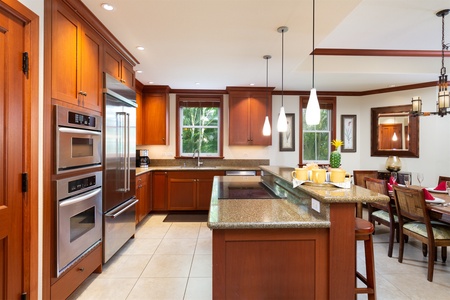 - Spacious kitchen with dual sinks, granite counters, and rich wood finishes   - Large windows invite natural light into the cooking space   - Pendant lighting over the island enhances the warm, inviting atmosphere