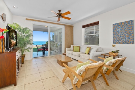 Relax in your bright living room with ocean views, tropical decor, and a gentle ceiling fan breeze.