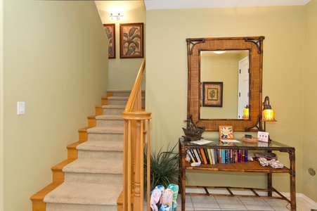 - Carpeted staircase leading to the upper level with framed artwork - Decorative console table with mirror adds charm to the entryway - Perfect blend of style and function for welcoming guests