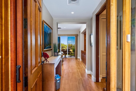 - Hallway with warm wood floors leading to living and dining areas with scenic views - Framed artwork and console table add decorative touches to the welcoming entryway - Recessed lighting and open layout provide a bright and airy path through the home