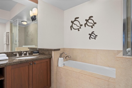 Unwind in your spacious bathroom featuring a deep soaking tub and separate glass shower, complete with tropical turtle wall art.