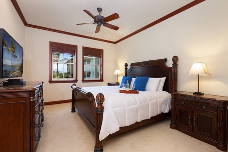 - Elegant bedroom with rich wooden bed frame, plush white bedding, and blue accent pillows   - Ceiling fan and natural light create a comfortable, airy feel   - Nightstands with warm lighting add to the inviting atmosphere