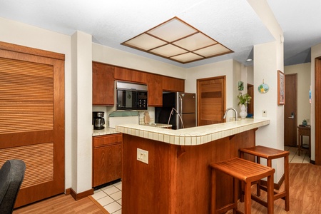 Your warm kitchen awaits with rich wood cabinetry, modern appliances, and a breakfast bar perfect for morning coffee or evening conversations.