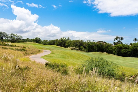 Winding golf cart path through fairways under sunny skies.
