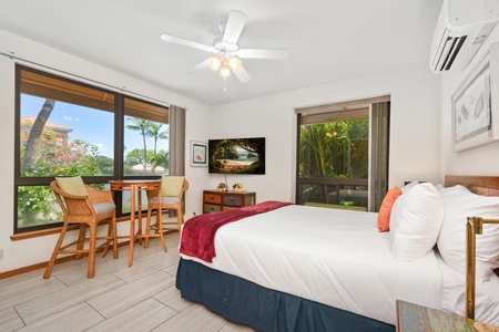 - King size bed with plush pillows and modern comfort under a ceiling fan breeze - Scenic windows offer tropical and golf course views from both sides - Dining table and rattan chairs create a cozy indoor breakfast spot