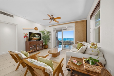 Relax in your bright living space with stunning ocean views through floor-to-ceiling windows and tropical breezes from the ceiling fan.