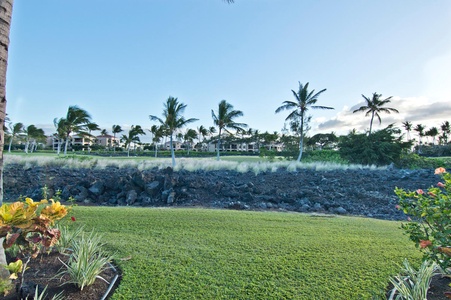 Scenic view of palm trees and manicured lawn set against a backdrop of lava rock.