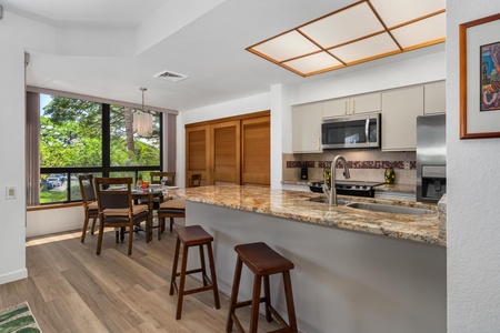 Picture yourself preparing meals at the spacious granite breakfast bar, then savoring them at your dining table overlooking lush greenery—your fully equipped kitchen awaits.