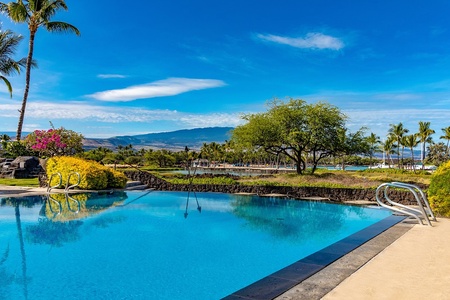 Infinity pool with crystal clear water overlooking mountains and tropical scenery.