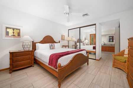 - Bright bedroom with a cozy queen bed, mirrored closet doors, and warm wood furniture - Soft lighting from dual nightstands and a ceiling fan ensure restful evenings - Stylish yet simple for a peaceful night after exploring the island