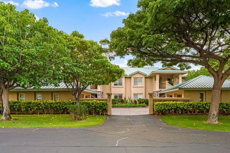 Elegant gated entrance framed by mature trees and manicured hedges.