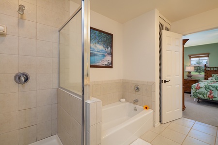 - Bright and clean bathroom featuring a full soaking tub perfect for evening relaxation - Neutral tile tones and soft lighting create a peaceful spa like atmosphere - Wall art adds a pop of color and island serenity to this soothing space