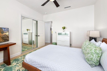 - Spacious bedroom includes a mirrored closet and tall modern dresser - Clean white walls and pops of green create a fresh relaxing space - Convenient layout with great storage and warm natural lighting
