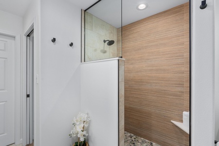 Walk in shower features a natural pebble floor and relaxing rainfall head.