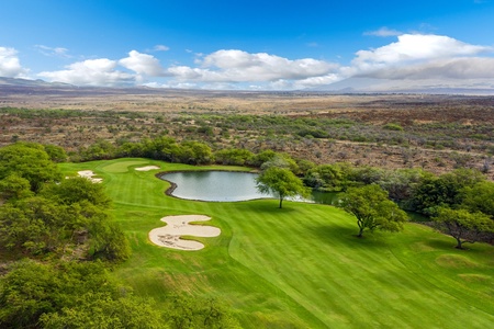 Scenic golf course with sand traps and a peaceful pond.