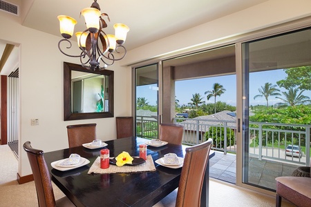 - Dining area with sliding glass doors leading to scenic balcony views   - Dark wood table set for four with tropical flower centerpiece adds charm   - Natural light pours in, blending indoor comfort with outdoor beauty