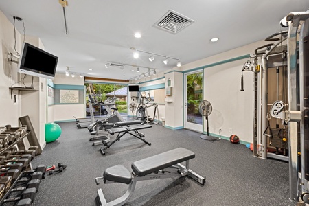 Compact, but fully-equipped fitness center, with cardio machines, weights, cable system, and TVs.