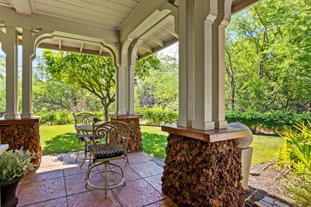 Covered lanai with garden views, dining table, and BBQ